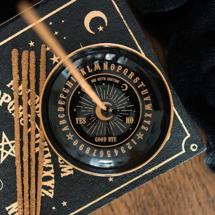 Zbliżenie na złote detale podstawki OUIJA w otoczeniu księżycowych rekwizytów ezoterycznych.