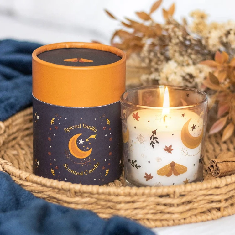 Płonąca świeca Autumn Magic w koszyku z gałązkami i ciepłym, przytulnym tłem.