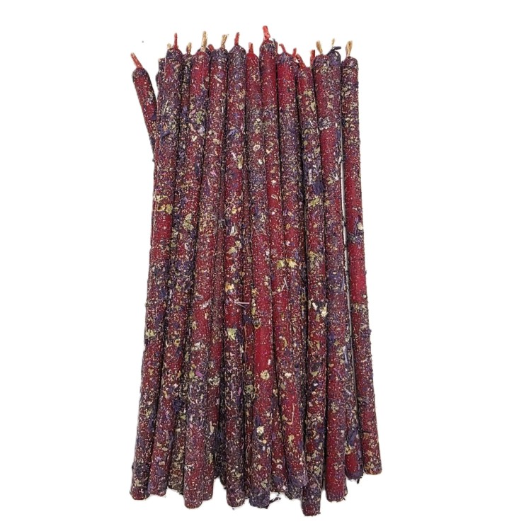 Cienkie czerwono–fioletowe świece rytualne pokryte suszoną szałwią.